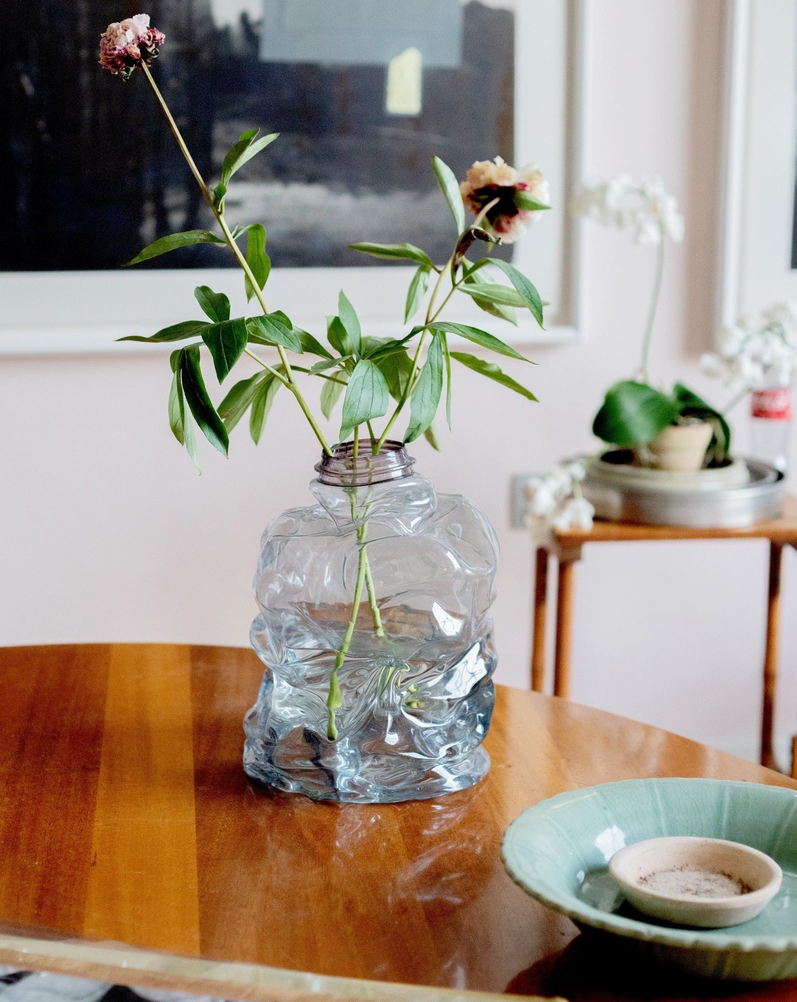 Medium blue handmade recycled plastic vase with pioneer flower on the table background