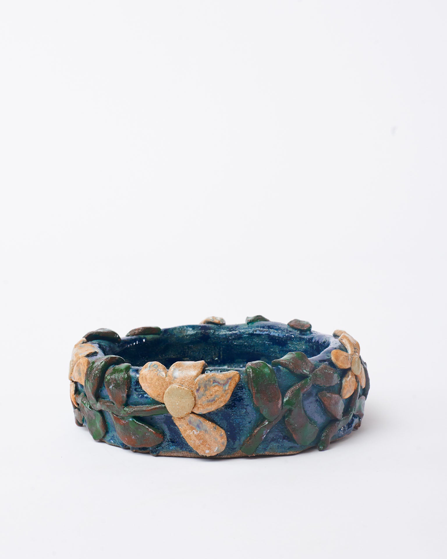 Blue handmade bowl with flower design in white background.